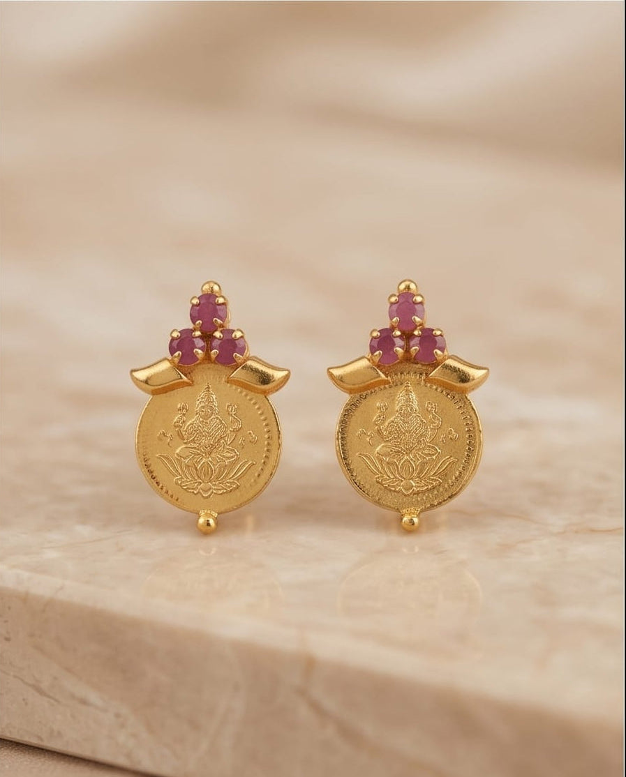 Gold earrings with gemstones on a beige background