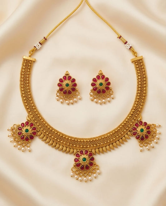 Gold necklace with matching earrings on a beige fabric background