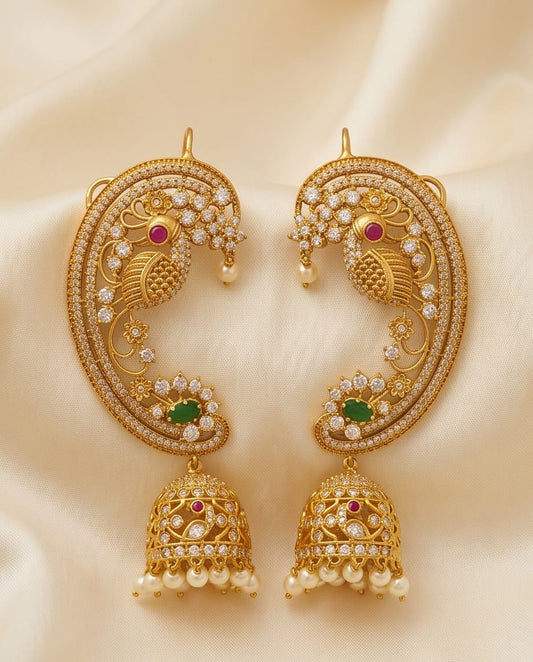 Gold earrings with intricate designs and gemstones on a beige fabric background