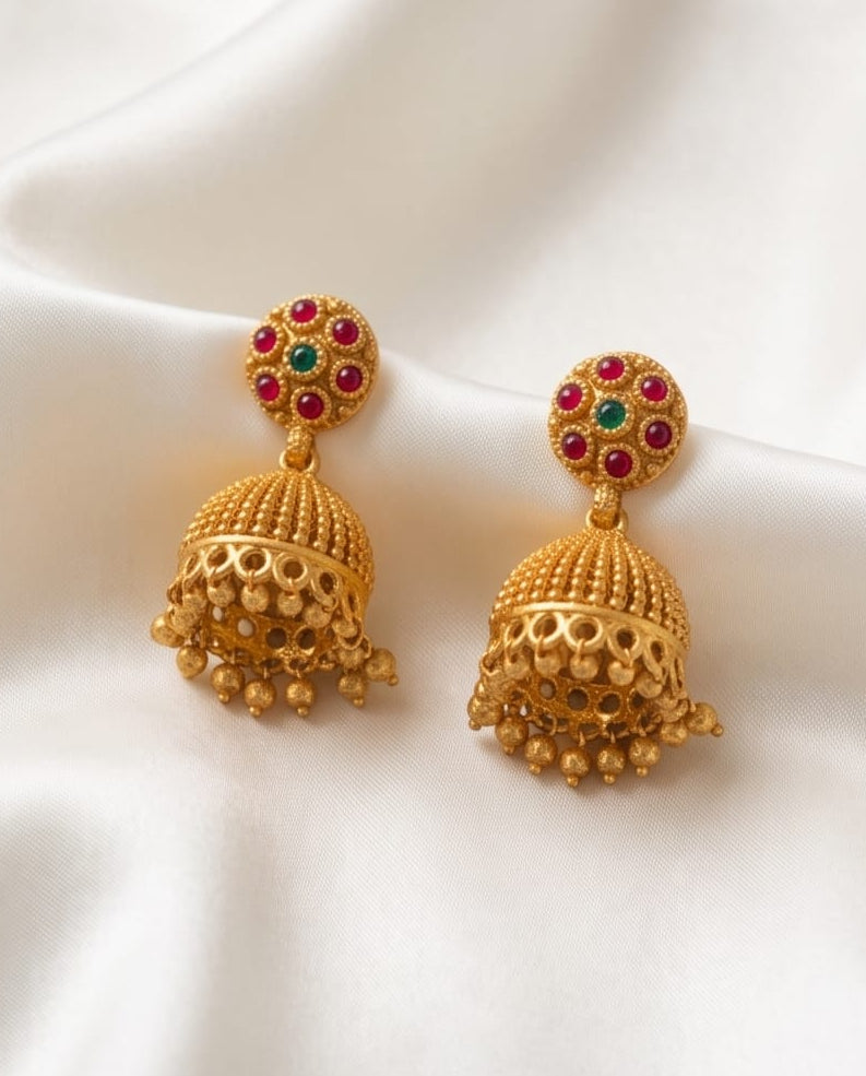 Gold earrings with gemstones on a white fabric background