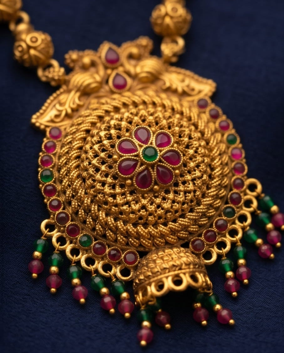 Gold necklace with red and green gemstones on a dark blue background