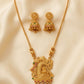 Gold necklace with intricate design and matching earrings on a beige fabric background