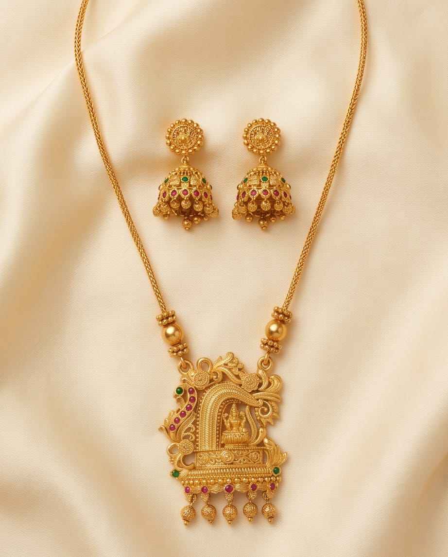 Gold necklace with intricate design and matching earrings on a beige fabric background