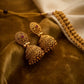 Gold earrings with red gemstones on a brown fabric background