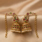Ornate gold earrings with pearls and gemstones on a beige fabric background