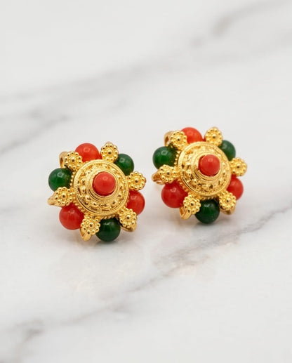 Pair of gold earrings with red and green beads on a white background