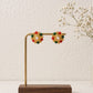 Decorative earrings on a wooden stand with a white background