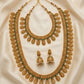 Gold necklace with green stones and matching earrings on a beige fabric background