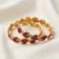 Gold bracelet with purple stones on a white background