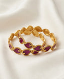 Gold bracelet with purple stones on a white background