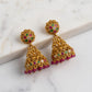 Gold earrings with colorful gemstones on a marble surface