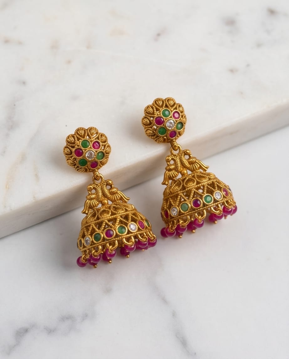 Gold earrings with colorful gemstones on a marble surface