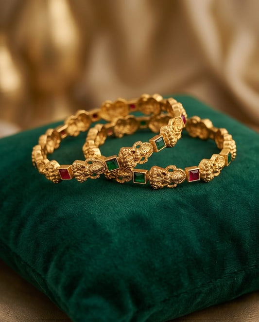 Gold bracelets with gemstones on a green cushion