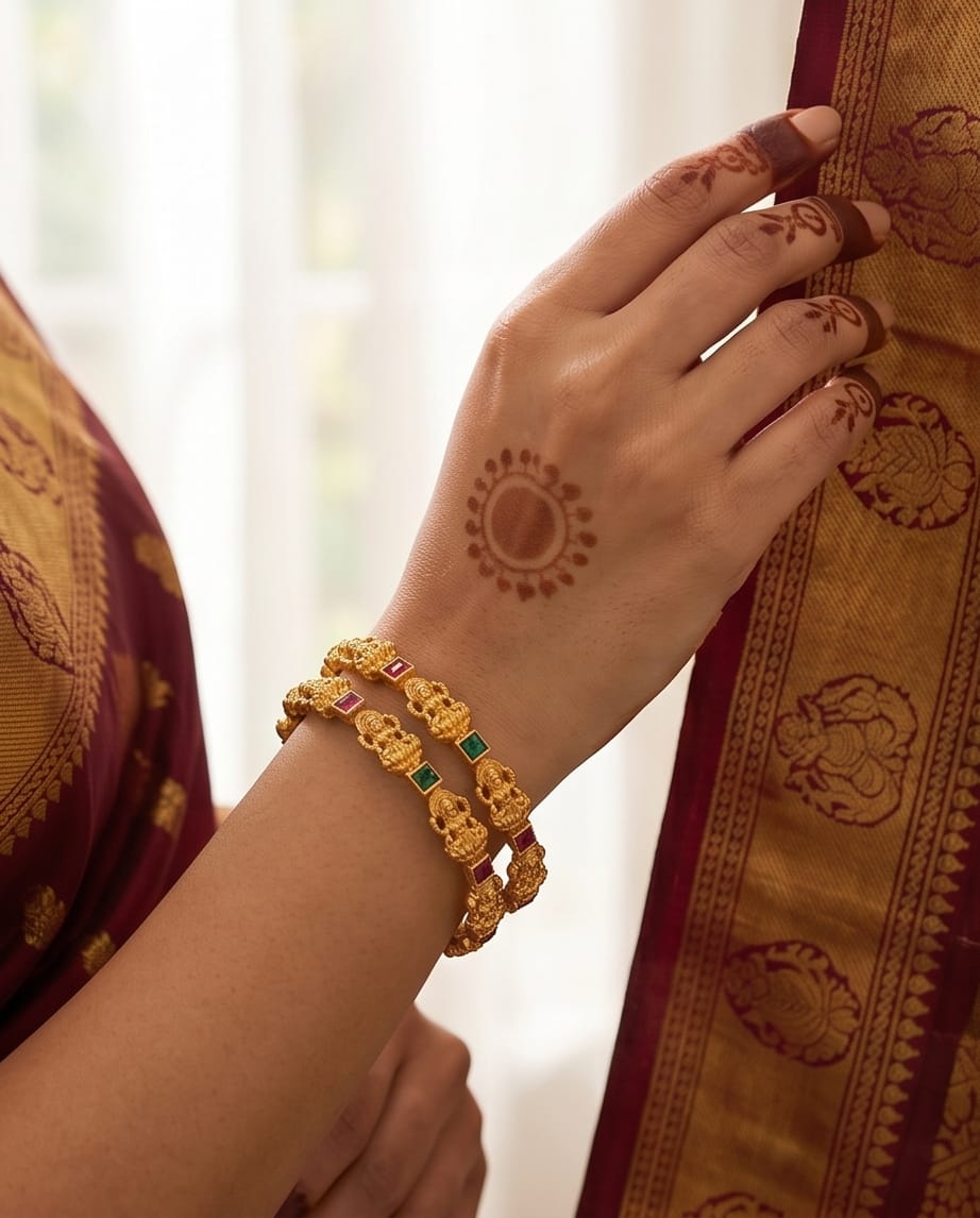 Hand with gold bracelet and henna design, wearing a traditional saree.
