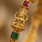Gold necklace with a figure and embedded red and green gemstones on a blurred gold background