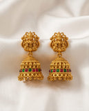 Gold earrings with red and green gemstones on a white fabric background