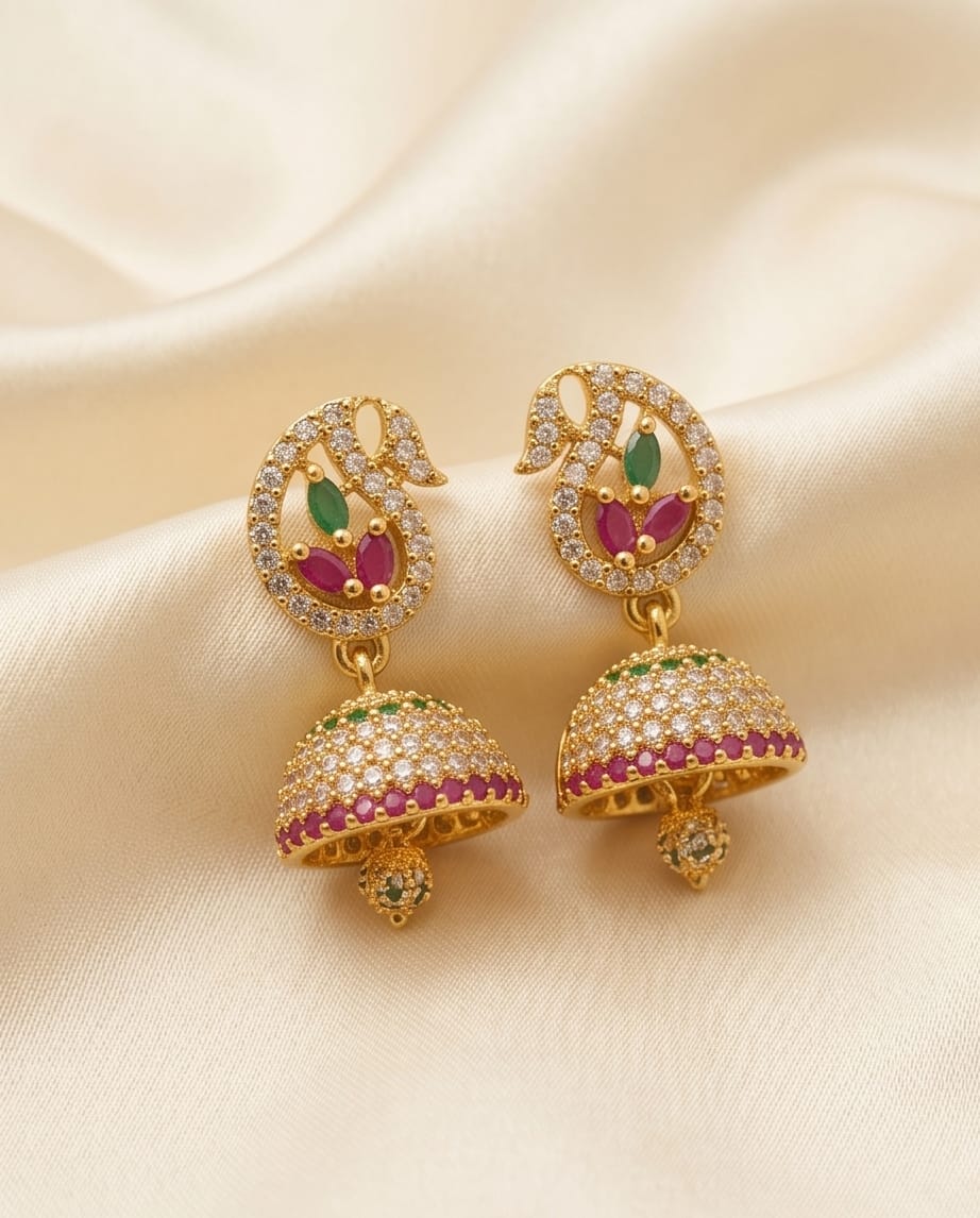 Gold earrings with gemstones on a beige fabric background