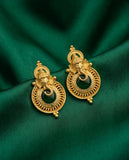 Gold earrings with black stones on a green fabric background