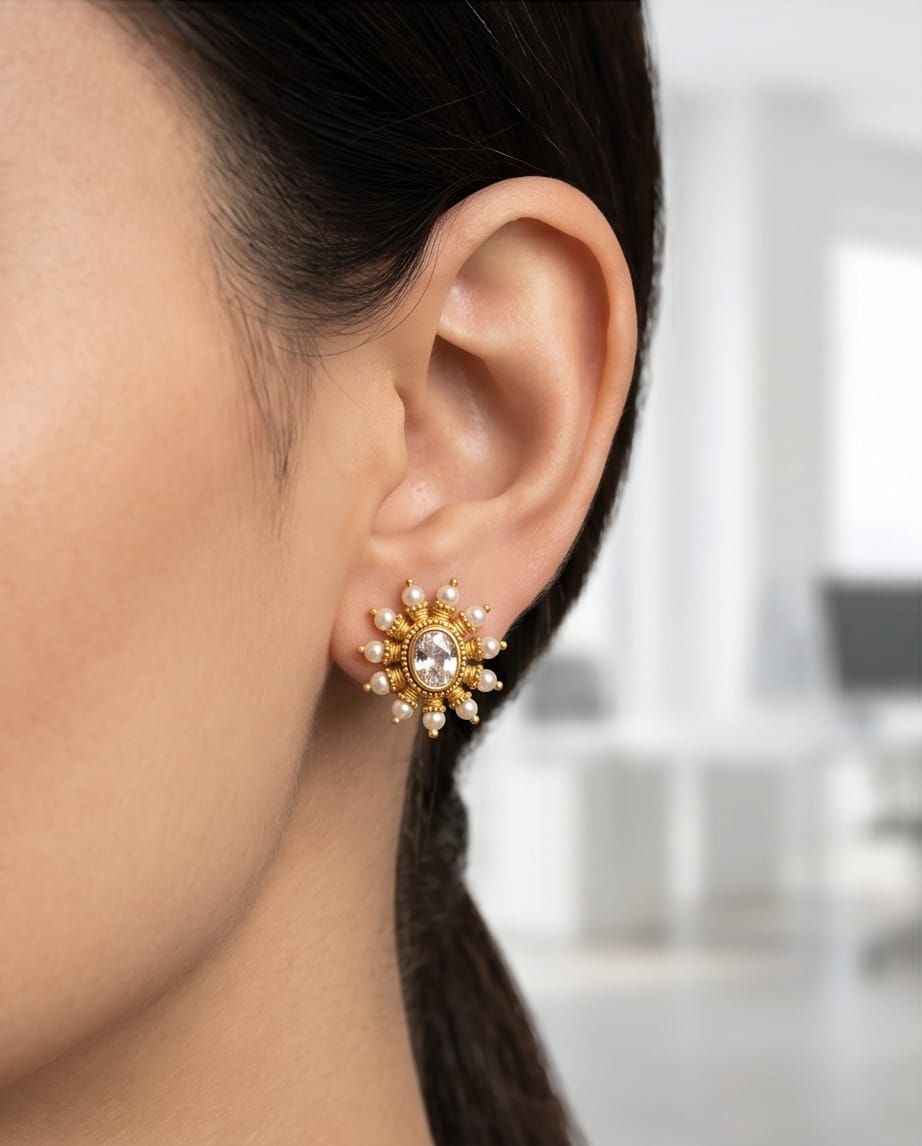 Close-up of an ear wearing a gold and pearl earring with a blurred background