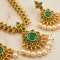 Gold jewelry with green stones and pearls on a light background