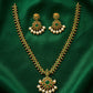 Gold necklace with green gemstones and pearl-like beads on a green fabric background