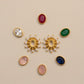 Collection of gold and gemstone earrings on a beige background