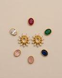 Collection of gold and gemstone earrings on a beige background