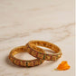 Pair of gold bangles with gemstones on a marble surface