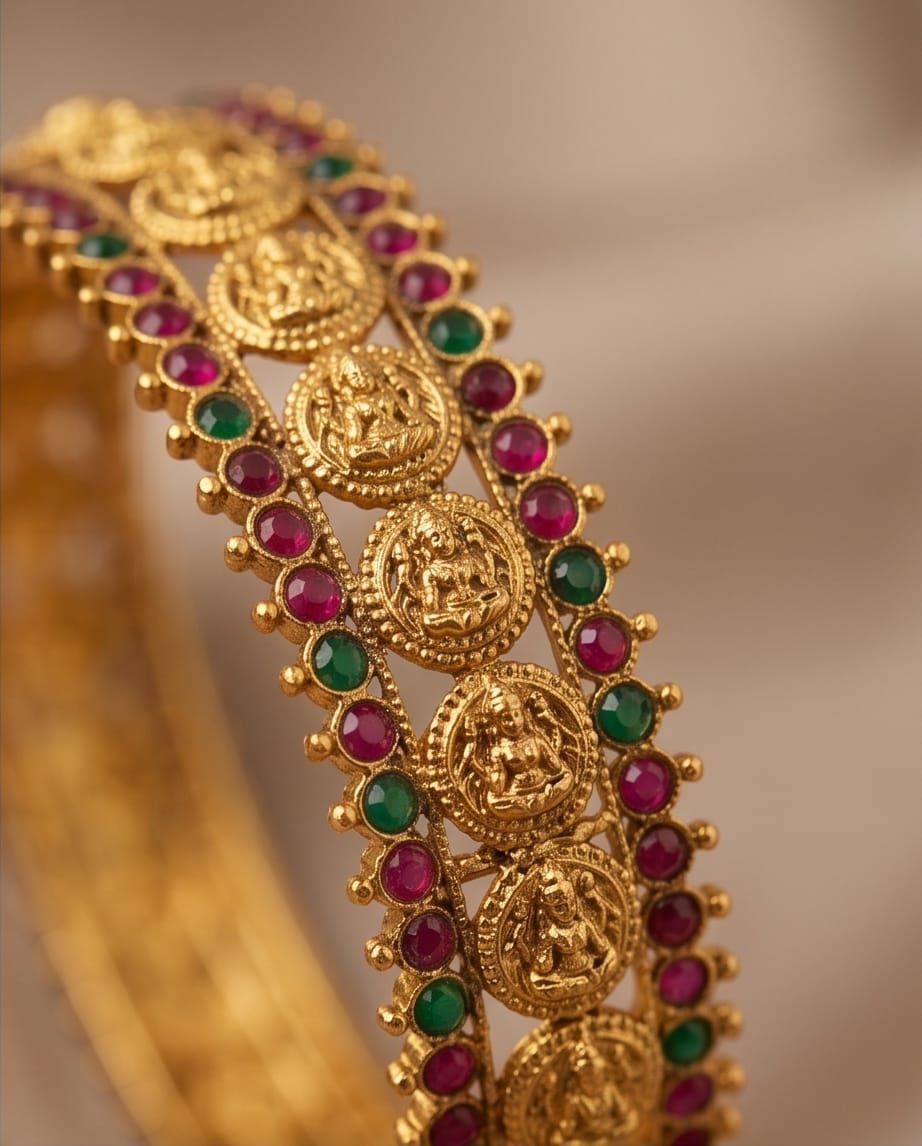 Gold bracelet with red and green gemstones on a blurred background