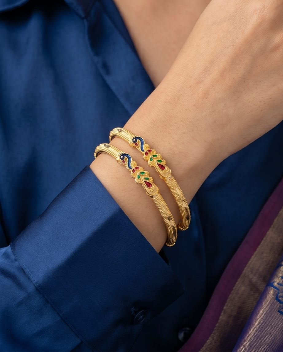 Gold bracelets with colorful accents on a wrist against a blue background