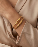 Gold bracelet with embedded stones on a beige background