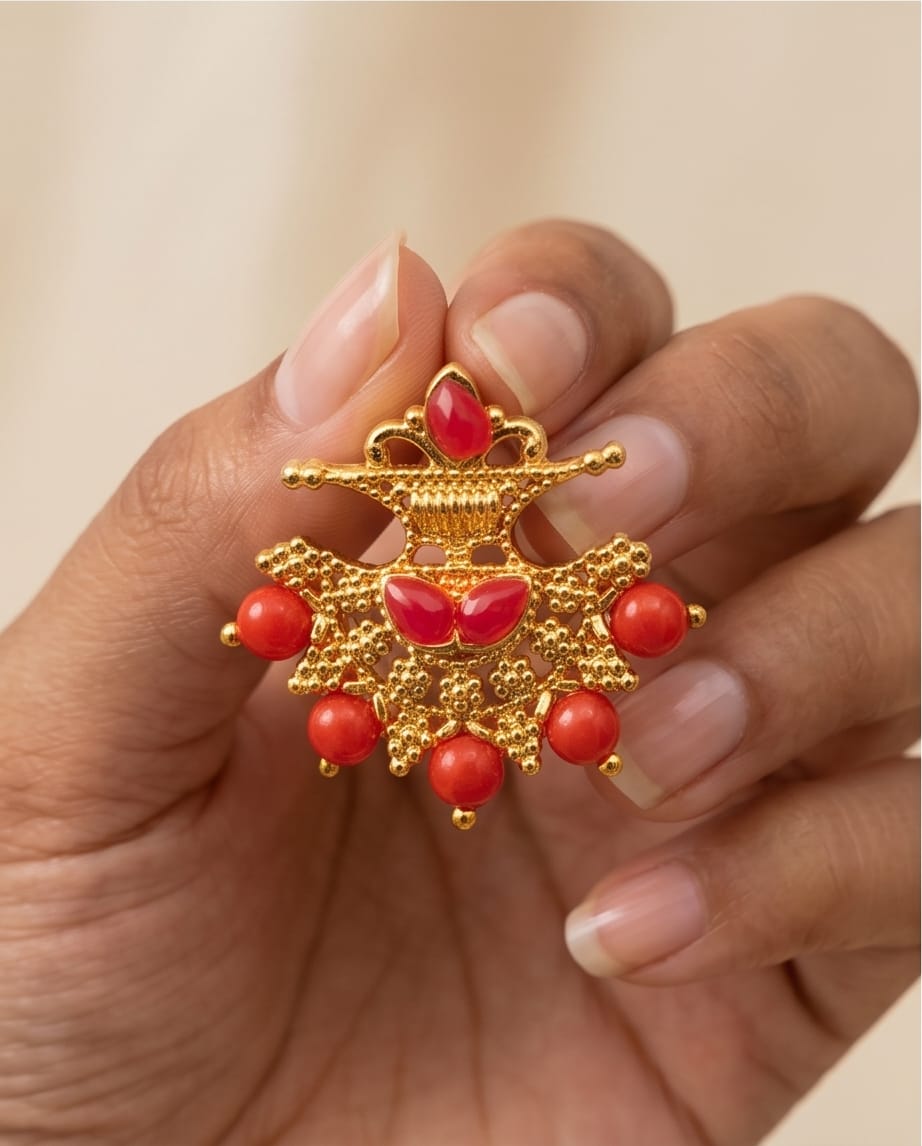 Gold ring with red gemstones held in a hand against a neutral background