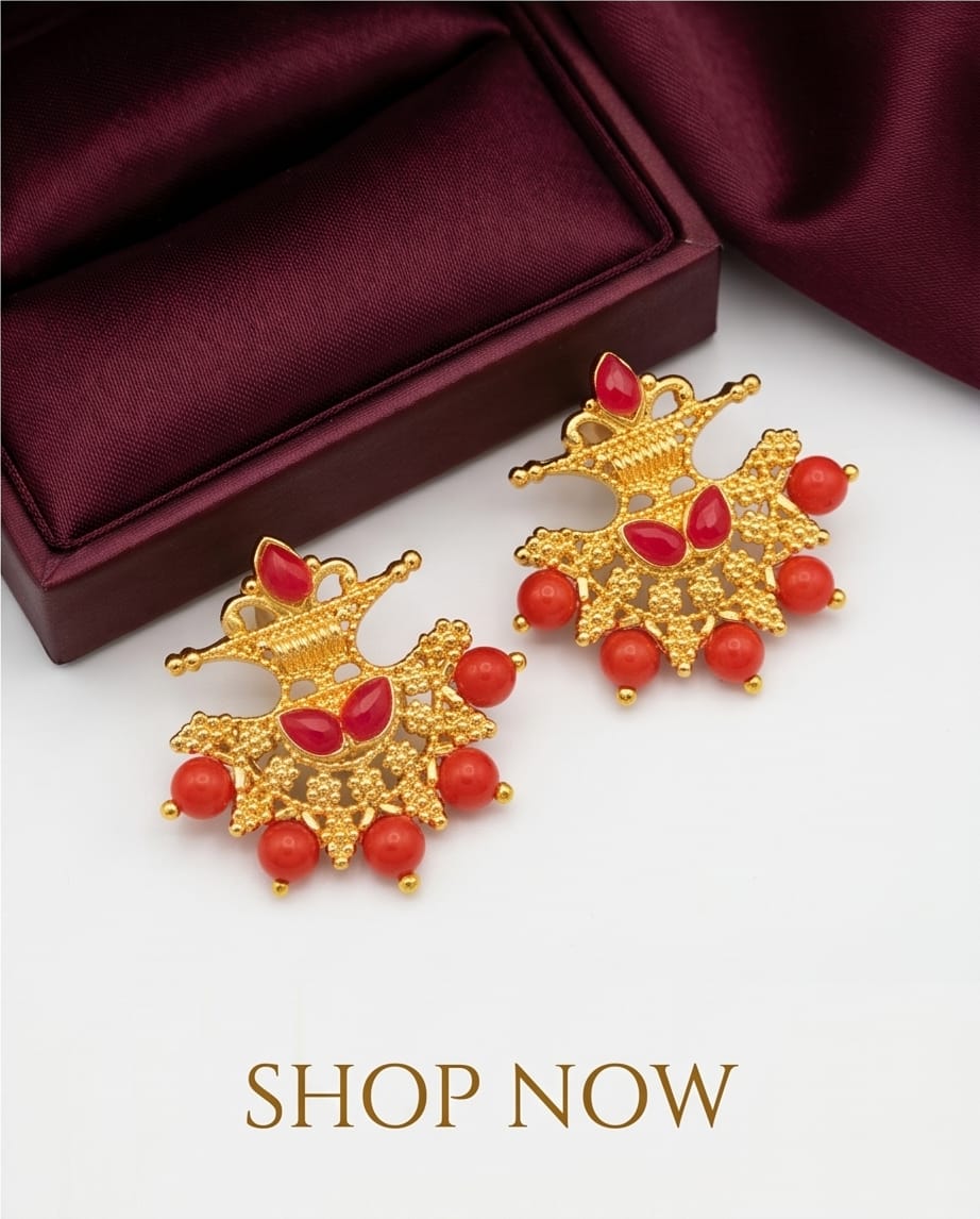 Gold earrings with red stones on a white surface with a maroon box in the background.