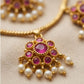 Gold necklace with pink gemstones and pearls on a beige background