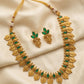 Gold necklace with green stones and matching earrings on a beige fabric background