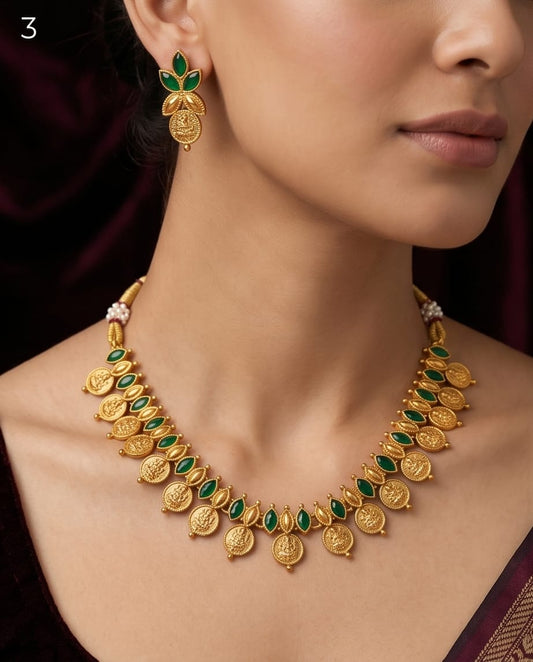 Gold necklace with green stones worn by a model against a dark background