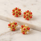 Gold earrings with red and pearl stones on a marble surface