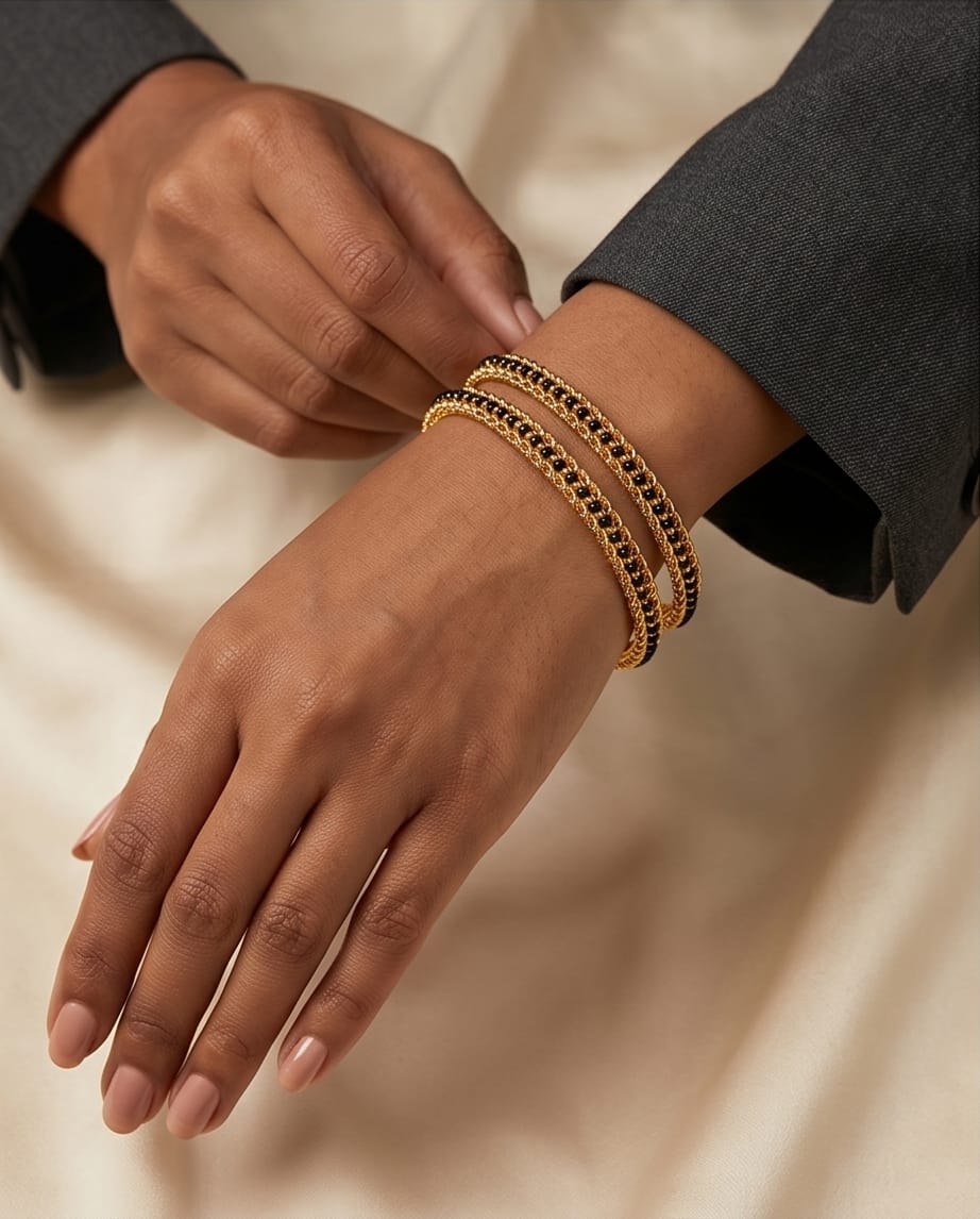 Close-up of a hand wearing a gold bracelet on a neutral background
