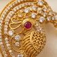 Gold jewelry with diamonds and a red gemstone on a beige background