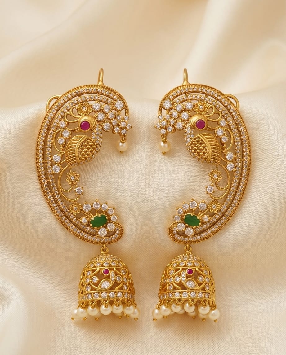 Gold earrings with intricate designs and gemstones on a beige fabric background