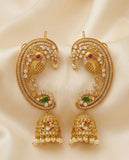 Gold earrings with intricate designs and gemstones on a beige fabric background