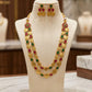 Gold necklace with colorful stones and matching earrings on a mannequin bust.
