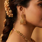 Close-up of a woman wearing gold earrings and a necklace with a blurred background