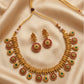 Gold necklace and earrings set on a beige fabric background