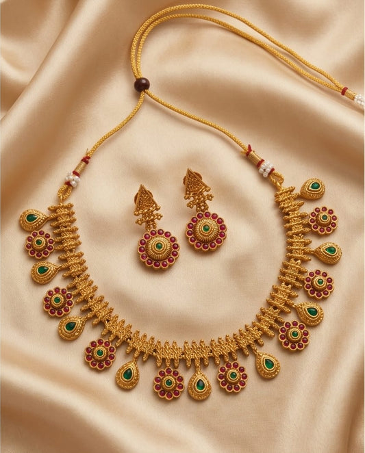 Gold necklace and earrings set on a beige fabric background