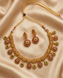 Gold necklace and earrings set on a beige fabric background