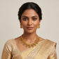 Woman wearing gold jewelry including a necklace and earrings on a neutral background