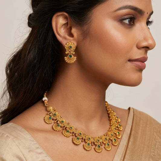 Woman wearing gold jewelry with green gemstones on a neutral background